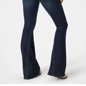 Mörkblå bootcut jeans med rå kant - Säljer ett par mörkblå bootcut jeans med ner tagen kant för dem var för korta. Jeansen har klassisk femficksdesign och är tillverkade i ett robust denimtyg. Perfekta för dig som gillar en retroinspirerad look med extra vidd vid benslutet.