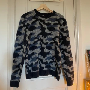 Blå stickad tröja - Tröja med blå/grått mönster, lite kamoflage. Den är strl s men inte tight, rätt rak i modellen. Supermysig och varm men passar tyvärr inte mig🌷