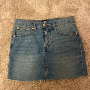 Blå jeanskjol från 157 med rå kant - Säljer en klassisk blå jeanskjol från 157 med fickor, bälteshällor och rå, fransig kant nertill! 💙 Kjolen har dragkedja och knapp framtill och är i en rak modell. Perfekt för dig som gillar en enkel och tidlös denimstil! Säljer pga att den ej är min stil och aldrig kommit till användning. 🤍