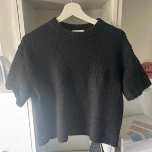 Svart stickad tröja från Gina Tricot - Mysig svart stickad tröja från Gina Tricot i ullblandning. Tröjan har korta ärmar. Använd c 2 gånger 
