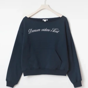 Mörkblå offshoulder sweatshirt Gina Tricot - Mörkblå sweatshirt från Gina Tricot med vit text 'Dansar vidare i livet' framtill. Tröjan har offshoulder-modell, lång ärm och en stor magficka. Mjuk insida och ribbade muddar, säljer på grund av att den inte kommer till användning, använd ca 2 gånger