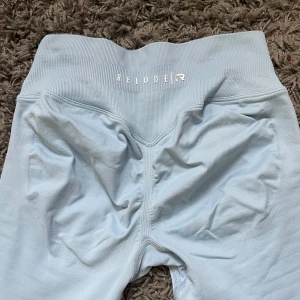 Ljusblå träningsleggings från Relode - Säljer ett par ljusblå träningsleggings från Relode. De är stretchiga och sitter tight, perfekta för träning. Materialet är mjukt och följsamt, och de har snygga detaljer bak. Storlek XS, aldrig använda och nypris är 699kr