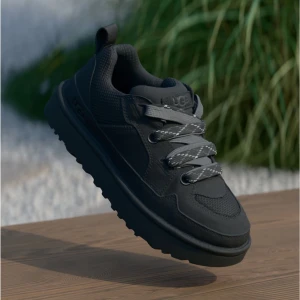 Svarta sneakers från UGG - Snygga svarta sneakers från UGG med robust sula och grå snören med reflexdetaljer. Skon har rund tå, platt sula och är tillverkad i en mix av syntet och skinn. Perfekt för dig som vill ha en stilren och bekväm sko till vardags.