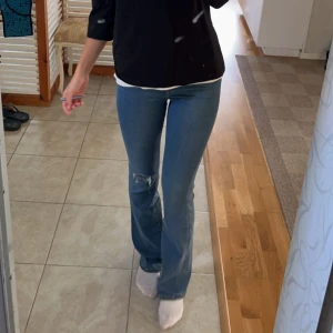 Levi's blå bootcut jeans med slitning - Snygga blå jeans från Levi's med bootcut passform och hög midja. Fint skick, inte alls mkt använda!