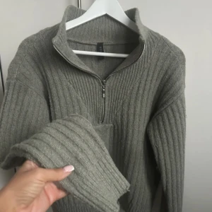 Olivgrön ribbstickad half zip-tröja från YAS - Mysig olivgrön ribbstickad tröja från YAS med half zip-dragkedja och hög krage. Tröjan har lång ärm och relaxed fit, perfekt för lager-på-lager. Snyggt stickat mönster framtill och breda muddar vid ärmslut. Endast använd en gång så i princip som ny! 