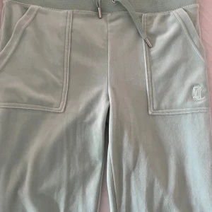 Mintgröna mjukisbyxor Juicy Couture S - Aldrig använda med lappen kvar. Supermjuka mintgröna mjukisbyxor från Juicy Couture med bred resår och snörning i midjan. Stora fickor fram och bak med logga och silverfärgade knappar. Perfekta för chill eller streetstyle. Klassisk Juicy-vibe och riktigt skön passform.