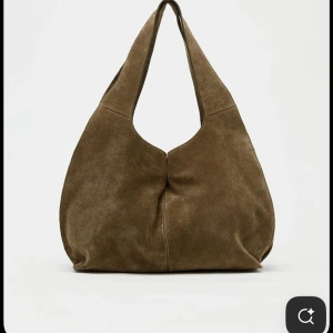 SÖKER följande: Brun mocka axelväska - Jag letar alltså efter väskan på bilden: Snygg axelväska i mjuk brun mocka med rundad form och breda axelband. Väskan har minimalistisk design utan synliga detaljer och passar perfekt för dig som gillar en chill och stilren look. Perfekt storlek för att få plats med allt du behöver under dagen. Den är från Zara 