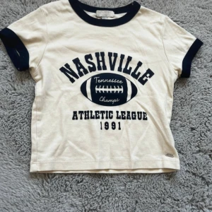 Topp med tryck - Fin topp i beige med mörkblå detaljer och tryck framtill. Liten i storleken💗