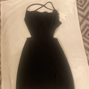 Svart långklänning från Bik Bok - Helt ny svart klänning från Bik Bok i storlek S! smala axelband som korsas i ryggen och en liten slits framtill.