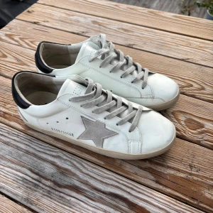 Vita Golden Goose skor.  - Snygga vita Golden Goose och off-white färgade snören. Tillverkade i skinn med klassisk rund tå och platt sula. Perfekta för en trendig och avslappnad look