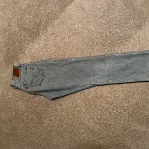 Levi's 501 ljusblå jeans straight fit - Klassiska Levi's 501 jeans i ljusblå denim med rak passform. Byxorna har fem fickor, knappgylf och den ikoniska läderpatchen bak i midjan. Perfekta för en avslappnad och tidlös stil.