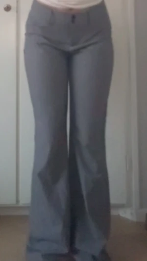 Gråa bootcut byxor med hög midja - Snygga gråa byxor med bootcut-modell och hög midja. Byxorna har klassisk design med fickor fram och stängs med knapp och dragkedja. Perfekta för dig som gillar en stilren och trendig look.