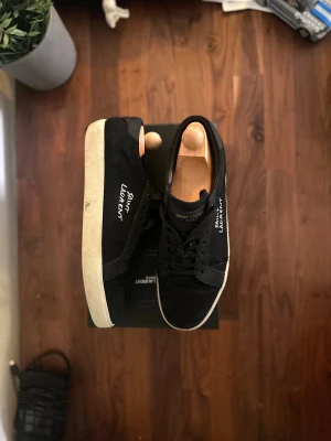 Saint Laurent court classic SL-06 - Tjena! Nu finns dessa paret tvär feta Saint Laurent court classic SL-06 skorna till salu. Dem är använda men ändå i helt okej/ bra skick. Inga direkta skador eller defekter utan bara dem vanliga tecknen för användning. OBS dem är INTE äkta, men ändå i topp kvalitet! Strkl 44 och box och alla accessoarer tillkommer:) 