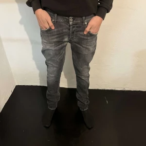 Grå jeans från Dondup  - Säljer ett par grå jeans från Dondup med snygg tvättad look och vita sömmar. Modellen har klassiska fem fickor, knapp och dragkedja i midjan samt raka ben med normal passform. Perfekt för dig som gillar streetstyle.