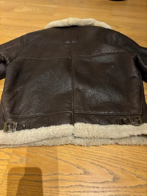 Brun bomberjacka med teddyfoder från Kellex - Säljer en brun bomberjacka från Kellex med mjukt fårull och krage i beige. Jackan har dragkedja framtill, två snedställda fickor och detaljer. Jacka är i äkta skinn. extra varm och chill för kalla dagar. Storlek S men passar även för större storlekar. Bra skick