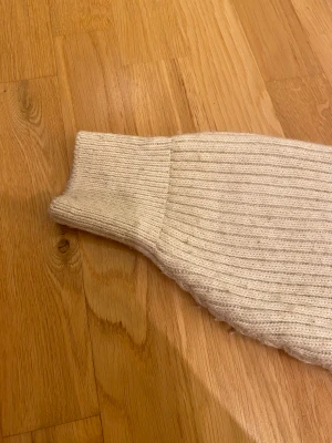 Beige ribbad kofta från H&M - Snygg beige kofta från H&M i storlek S. Modellen är ribbstickad med v-ringning och har tre stora knappar framtill. Koftan har långärmade ärmar och är gjord i mjukt stickat material som känns mjukt.