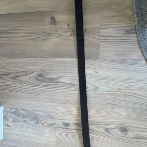 Svart skärp från Kappahl  - Stilrent svart bälte från Kappahl med en klassisk, fyrkantig metallspänne. Perfekt till jeans eller kostymbyxor när du vill ha en clean och tidlös look. Bältet är smalt och enkelt, vilket gör det lätt att matcha med olika outfits.