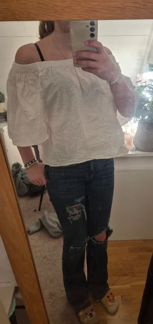 Vit offshoulder blus med struktur - Säljer en vit blus med offshoulder och trekvartsärm. Blusen har en lätt strukturerad, rutig yta och är croppad i modellen. Perfekt för dig som gillar en chill och luftig stil. Materialet känns som bomull och toppen har en avslappnad passform.