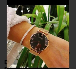 Svart och guld klocka från Denzel - Stilren klocka från Denzel of Sweden med svart urtavla och romerska siffror. Boetten och det meshade armbandet är i guldtonad metall som ger en lyxig vibe. Perfekt accessoar för dig som gillar minimalistisk design och snygga detaljer.