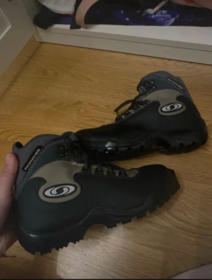 Salomon skid skor - Säljer ett par svarta och grå skid skor från Salomon i storlek 37. Skorna har grov sula för extra grepp, snörning och Salomon-logga på sidan. Materialet är en mix av syntet och textil, perfekt för utomhusaktiviteter och äventyr. Köpta för 3500. Använd 1 gång 