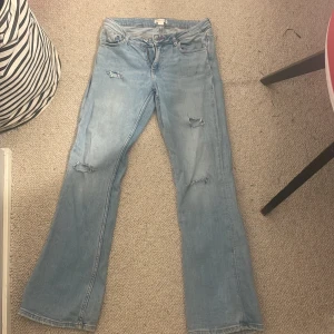 Bootcut jeans från Gina Tricot ljusblå - Säljer ett par ljusblå bootcut jeans från Gina Tricot i storlek 158. Jeansen har slitna detaljer på framsidan, klassisk femficksdesign och är tillverkade i mjukt denimtyg. Perfekt för dig som gillar en avslappnad och trendig look.