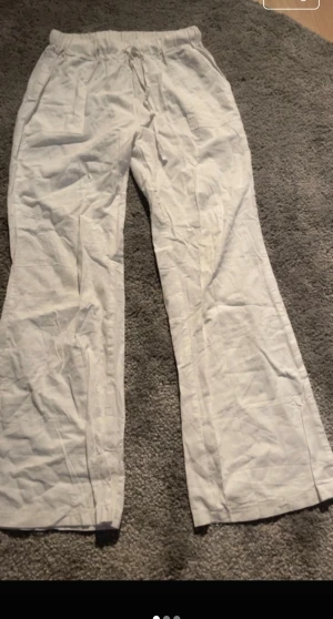 Vita linnebyxor med snörning - Luftiga vita linnebyxor med dragsko i midjan och raka, lite vidare ben. Perfekta för varma dagar och enkel stil. Byxorna har fickor på sidorna och är tillverkade i ett lätt och svalt linnematerial.