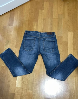 Emilio  jeans mörkblå straight - Säljer ett par emilio jeans i mörkblå tvätt med snygga slitningar. Modellen har klassisk femficksdesign, raka ben och normal passform. Jeansen är tillverkade i stretchig bomull för extra komfort och har Replay-logga på bakfickan.