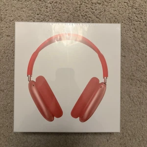 AirPods Max - Apple AirPods Max i röd färg, trådlösa over-ear hörlurar med aktiv brusreducering och hög ljudkvalitet. Produkten är i originalförpackning och ser ut att vara i nyskick utan synliga defekter eller slitage.
