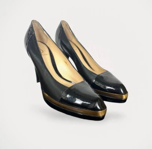 Svarta pumps från Yves Saint Laurent - Säljer min tjejs snygga svarta pumps från Yves Saint Laurent med elegant spetsig tå och låg klack. Skorna har en guldtonad detalj längs sulan och är tillverkade i blankt skinn. Perfekt för dig som gillar klassisk och lyxig stil med en modern twist.