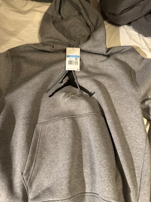 HELT NY Jordan hoodie - Säljer en helt ny grå Jordan-hoodie i storlek M. Aldrig använd och lappen sitter fortfarande kvar. Snygg, stilren och perfekt för både vardag och träning.