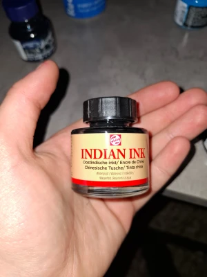 Indian ink - Märke och produkt: Talens Indian Ink, svart. Volym: 30 ml. Egenskaper: Bläcket är vattenfast när det har torkat och har utmärkt ljusäkthet. Det är baserat på sotpigment och shellack. Användning: Kan appliceras med pensel, stålpenna, airbrush med mera. Tillgänglighet: Produkten säljs hos konstnärsmaterialhandlare både online och i fysiska butiker.