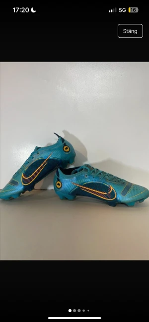 Nike blå fotbollsskor Flyknit - Säljer ett par grymma Nike fotbollsskor i blått med snygga gula och röda detaljer. Skorna har snörning, rund tå och platt sula med dobbar. Ovandelen är tillverkad i syntet och Flyknit-material för extra komfort och passform. Perfekta för dig som vill sticka ut på planen!