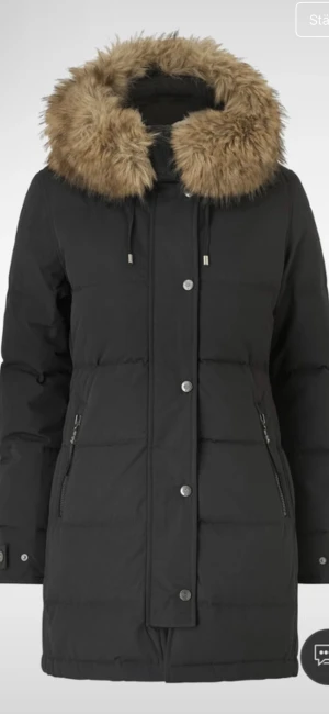 Svart pufferjacka Hollies subway utan päls - Svart pufferjacka från Hollies med stor huv. Jackan har dragkedja och knappar framtill, två sidofickor med dragkedja och snygga detaljer vid ärmslut. Insidan har coolt Arctic Expedition-tryck.