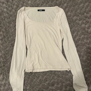 Vit långärmad topp från Bikbok - Säljer en enkel och stilren vit långärmad topp från Bikbok i storlek S. Toppen har en rundad, lite djupare halsringning och är figurnära i modellen. Perfekt att matcha med jeans eller kjol för en clean look.