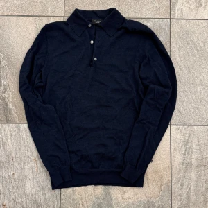 Martinique merino tröja  - Snygg mörkblå pikétröja från Martinique i 100% merinoull. Tröjan har klassisk krage, tre knappar framtill och långärmad design. Perfekt för dig som gillar stilrena och bekväma plagg med lite extra lyxig känsla. Hör av dig vid funderingar!