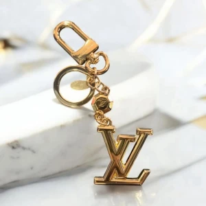  Vuitton guld nyckelring med -logo - Exklusiv  Vuitton nyckelring i guldtonad metall med stor -logo och detaljerad ring med ingraverad text. Snygg och lyxig accessoar som ger din väska eller nycklar en extra touch av stil. Perfekt för dig som gillar statement pieces och designer.