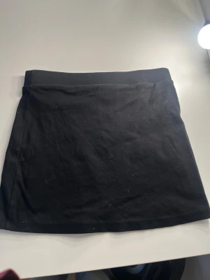 Svart kortkjol från Gina Tricot - En enkel svart kortkjol från Gina Tricot i mjuk bomull. Har aldrig kommit till användning