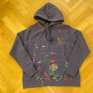 Mörkgrå hoodie från Gallery Dept. - Säljer en mörkgrå hoodie från Gallery Dept. med huva och snörning. Tröjan har färgstänk i grönt, rött, lila och vitt på framsidan och subtila vita penseldrag på baksidan. Tryck med 'DEPT. de la GALERIE' på bröstet och stor känguruficka framtill.