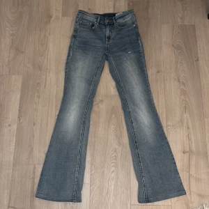 Blå bootcut jeans från Vero Moda - Snygga blå jeans från Vero Moda med klassisk bootcut passform och fem fickor. Jeansen har en  låg midja och är tillverkade i mjukt denim-material. Perfekt för dig som gillar retrovibbar och vill ha ett avslappnat men trendigt uttryck.
