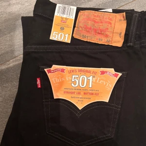 Nya svarta Levi's 501 jeans straight leg - Jag har ökat en storlek😀 och har oanvända helt nya svarta Levi's 501 jeans med klassisk straight leg och button-fly. Original fit med ikonisk röd Levi's-tag på bakfickan och tydliga etiketter. Perfekt för dig som gillar tidlös stil och vill ha ett par jeans som alltid funkar.
