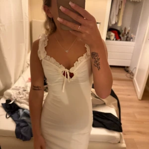 Vit spetsklänning med volangdetaljer - Supersöt vit klänning från nelly med breda axelband i spets och volangdetaljer. Figurnära passform, omlottdesign vid bysten med knyt och v-ringning. Perfekt för sommarens alla tillfällen! aldrig använd och prislapp är kvar!