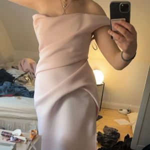 Ljusrosa ofshoulder bal klänning  - Säljer min balklänning som bara är använd en gång. Den är superfin och lite unik, med en slits vid benet och öppen rygg. Jag är 174 cm och den sitter perfekt i längden. Finns lite smuts längst ner bak + lite brun utan sol på insidan men inget som syns när man har den på. Nypris 2700 kr.