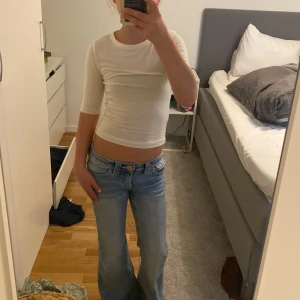 Vit croppad topp från H&M - Säljer en enkel och stilren vit croppad topp från H&M. Toppen har trekvartsärm och är figurnära med rund halsringning. Perfekt att matcha med jeans eller kjol för en clean look.