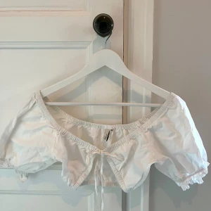 Vit croptop från NLY Trend 34 - Vit topp från Nelly i storlek 34 med knyt fram. En liten fläck fram, se sista bilden.