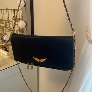 Marin blå Zadig Voltaire väska  - Rock clutch väska, marinblå med guld detaljer. Äkta, köpt på Vestiaire collective för 3400kr för ungefär ett år sedan. Bra skick. Kostar ungefär 4300kr ny. Har en lång och en kort kedja man kan växla mellan. 