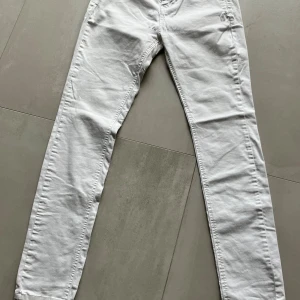 Vita jeansbyxor från Stradivarius - Snygga vita jeansbyxor från Stradivarius med klassisk femficksdesign och smal passform. Byxorna har bälteshällor, knappstängning och är tillverkade i ett mjukt bomullstyg med lite stretch. Perfekta för en fräsch och clean look.