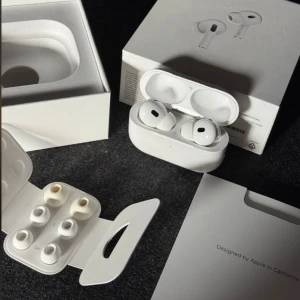AirPods Pro (2nd generation) - Apple AirPods Pro 2nd gen med originalförpackning, laddningsetui och extra öronproppar i olika storlekar. Aktiv brusreducering, transparensläge och trådlös laddning. Mycket gott skick, fullt fungerande och 100% batterihälsa. Minimalt slitage synligt.