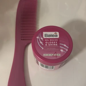Balea Gel Wachs Glossy & Shine - Balea Gel Wachs Glossy & Shine i en snygg rosa burk, perfekt för att skapa glansiga och flexibla frisyrer. Kommer tillsammans med en matchande lila kam i plast. Ger stadga och glans till håret för en polerad look.