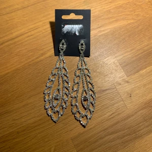 Två par örhängen från Glitter  - Två par silverfärgade örhängen från Glitter. Nya och oanvända 