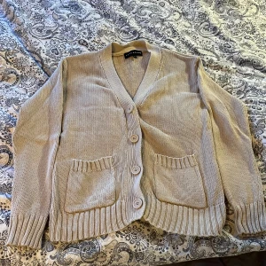 Beige stickad kofta  - Snygg beige stickad kofta från Pahladium i storlek L men passar även M. Koftan har ribbade muddar, två framfickor och fyra stora knappar framtill.Aldrig använd, säljer då den är lite tajt på mig